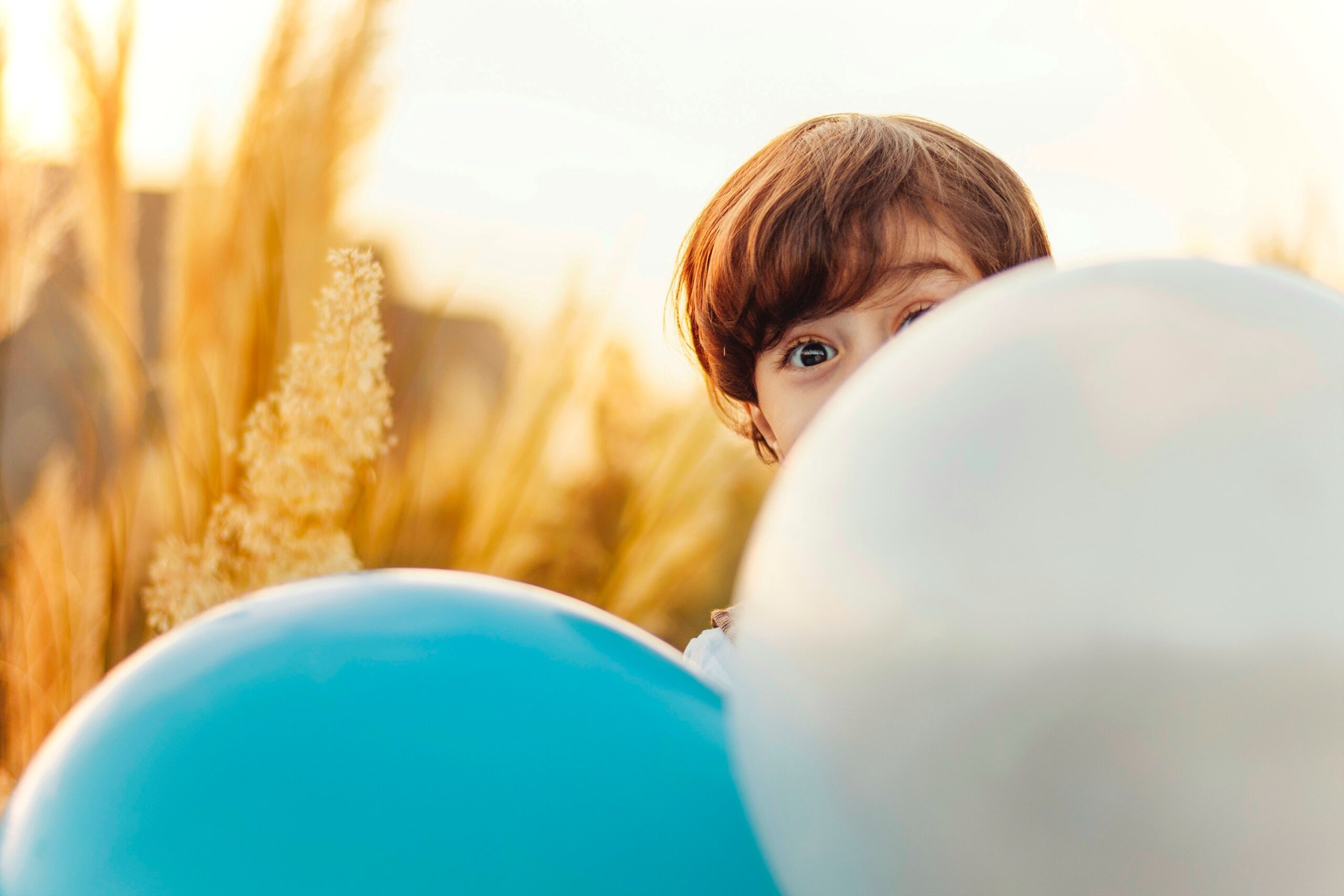 picture of a young boy behind two balloons