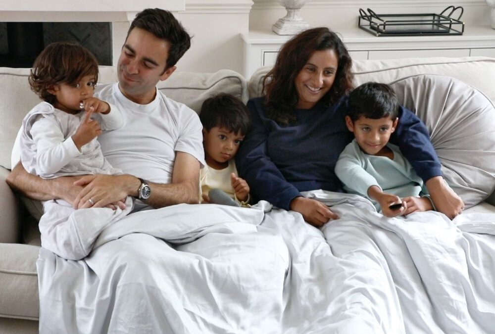 Founder Anamika with her partner and two children on a sofa with blankets