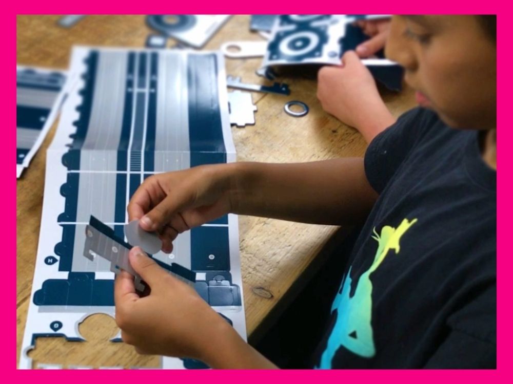 Young boy building a telescope from cardboard cut outs