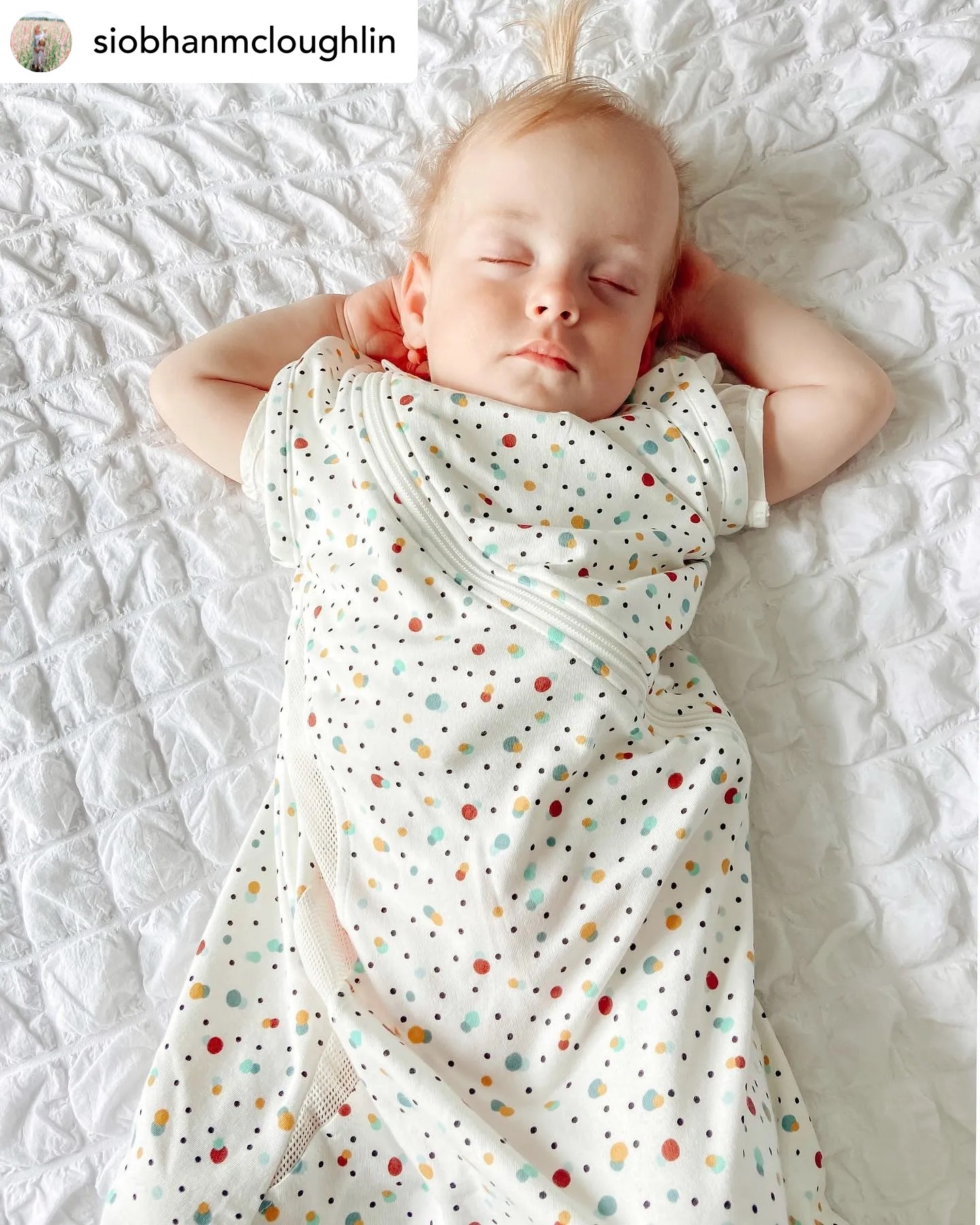 Baby asleep with hands behind head in cot